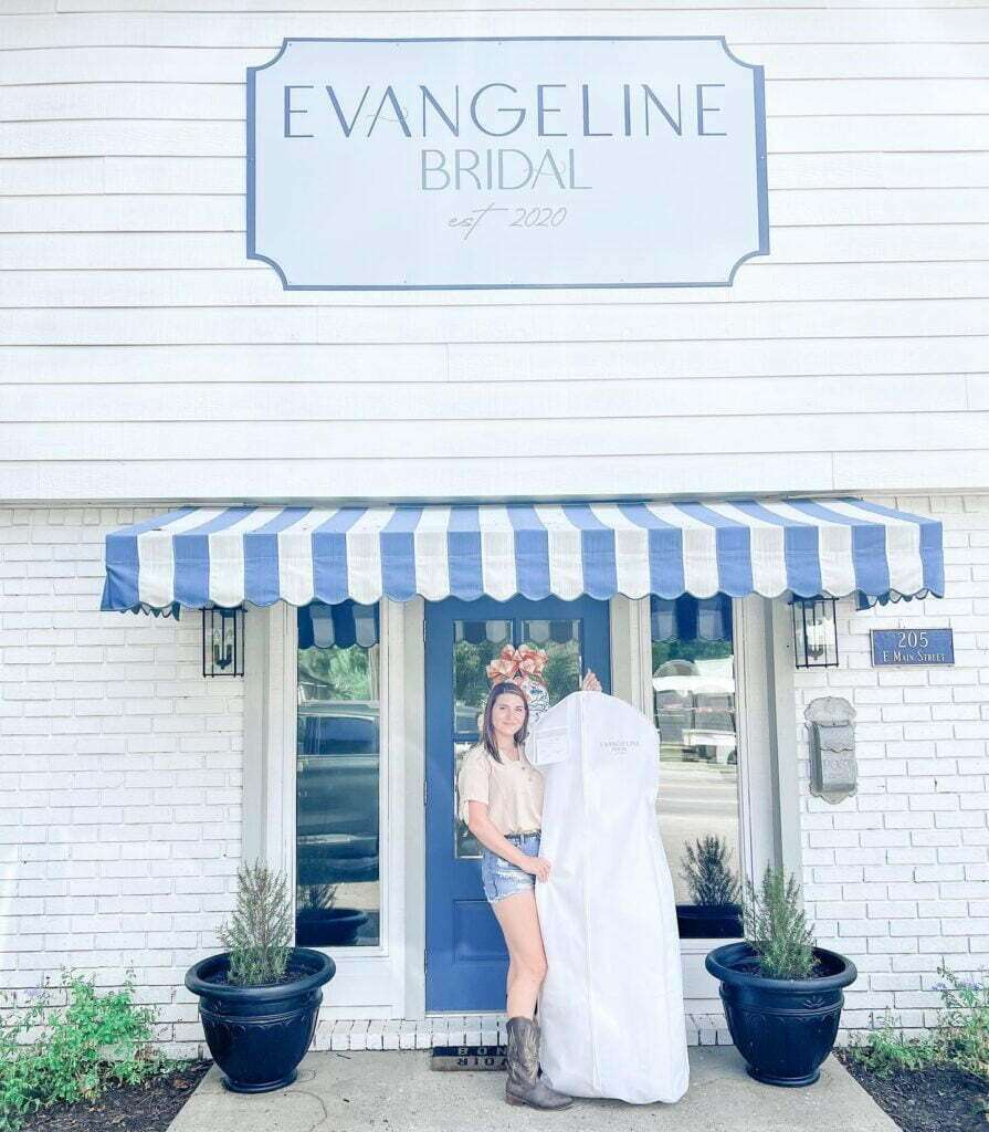in front of Evangeline Bridal Boutique is a future bride holding her wedding gown